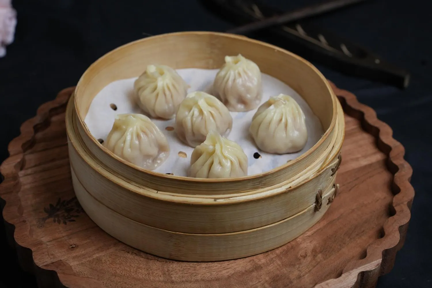 Steamed soup dumplings served in bamboo steamer at Dumpling Party Hunan Cuisine, a Chinese Restaurant in Sugar Land